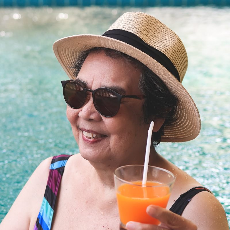 Roselani Place | Senior woman by the pool with a cocktail